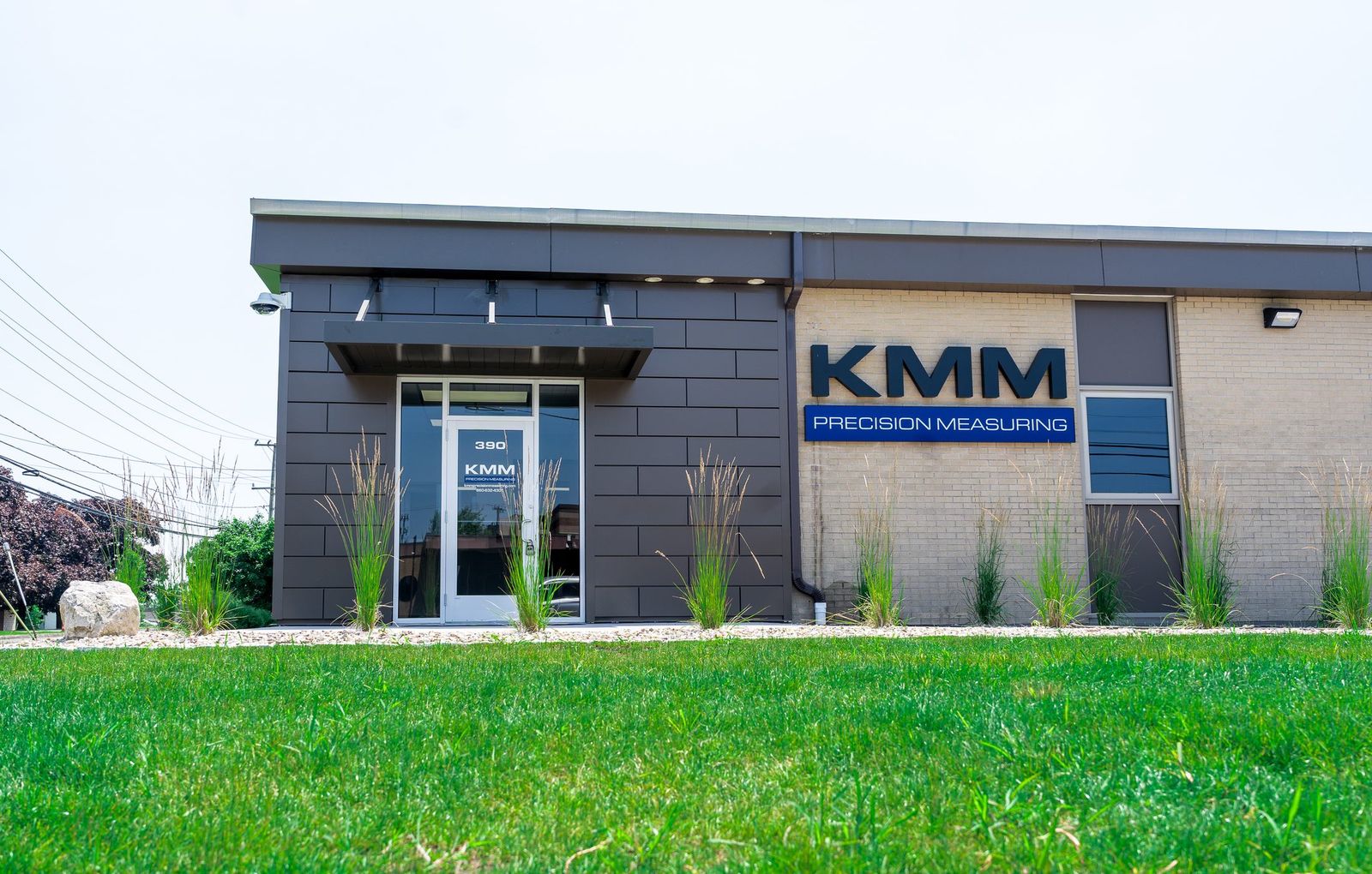 Black metal entrance canopy over the door at KMM Precision Measuring with landscaped grounds by Manchester Awning