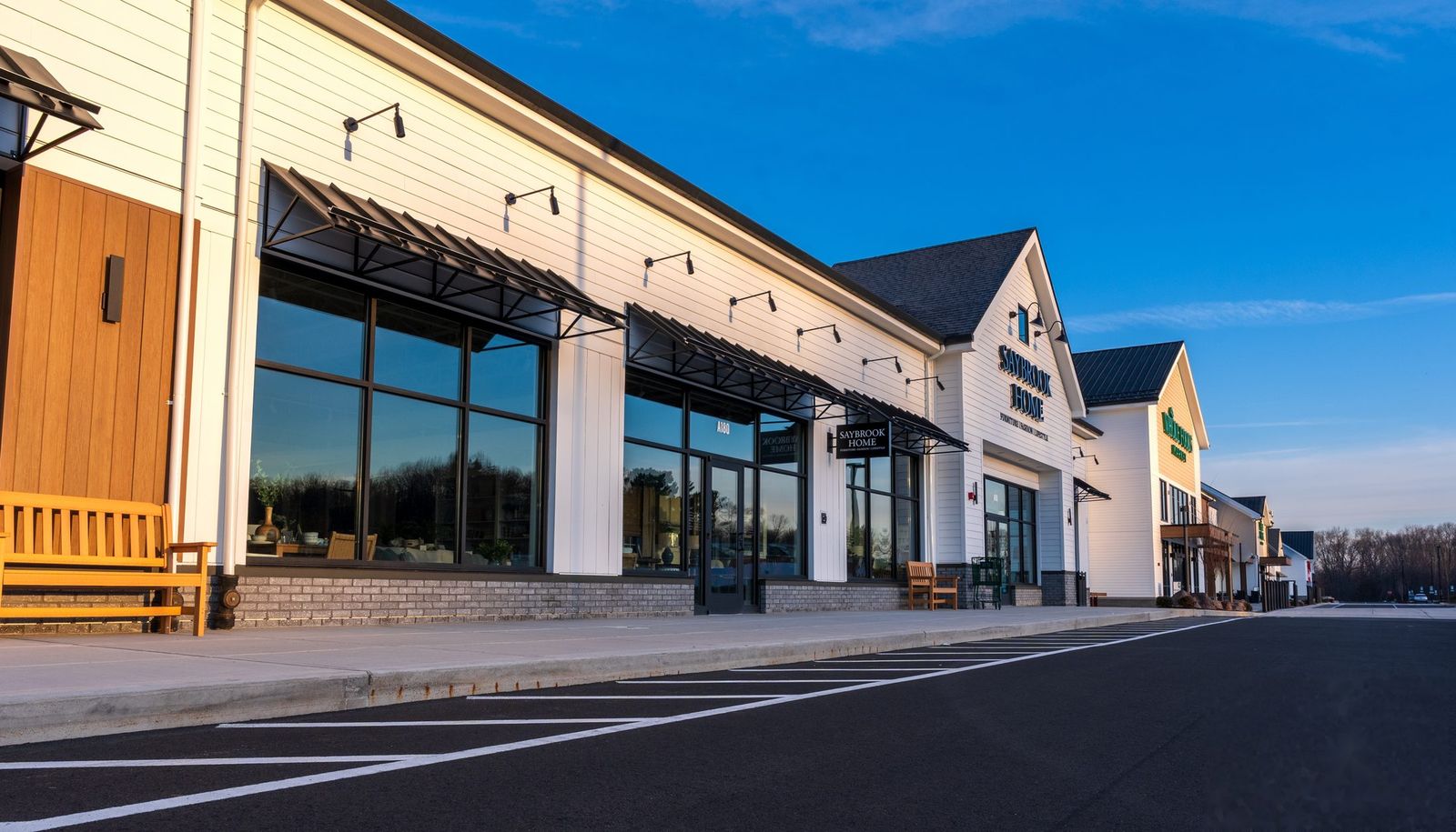Row of black architectural metal awnings across an upscale Connecticut retail plaza at golden hour, by Manchester Awning