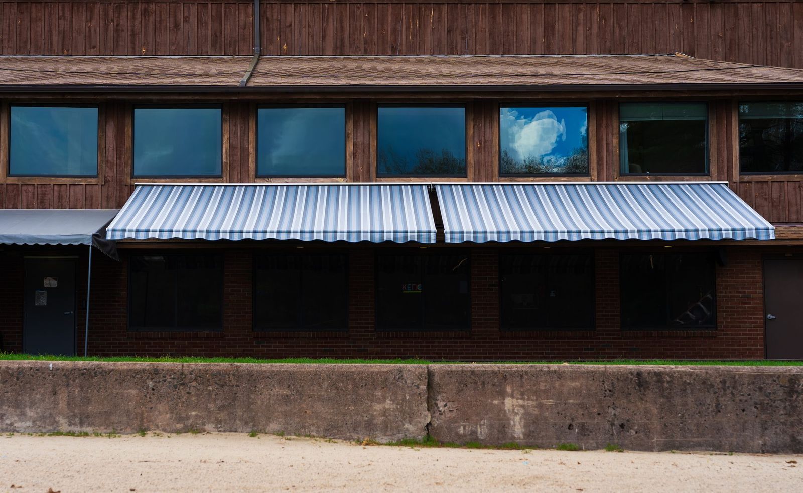 Blue and white striped fabric window awnings on a brick building by Manchester Awning