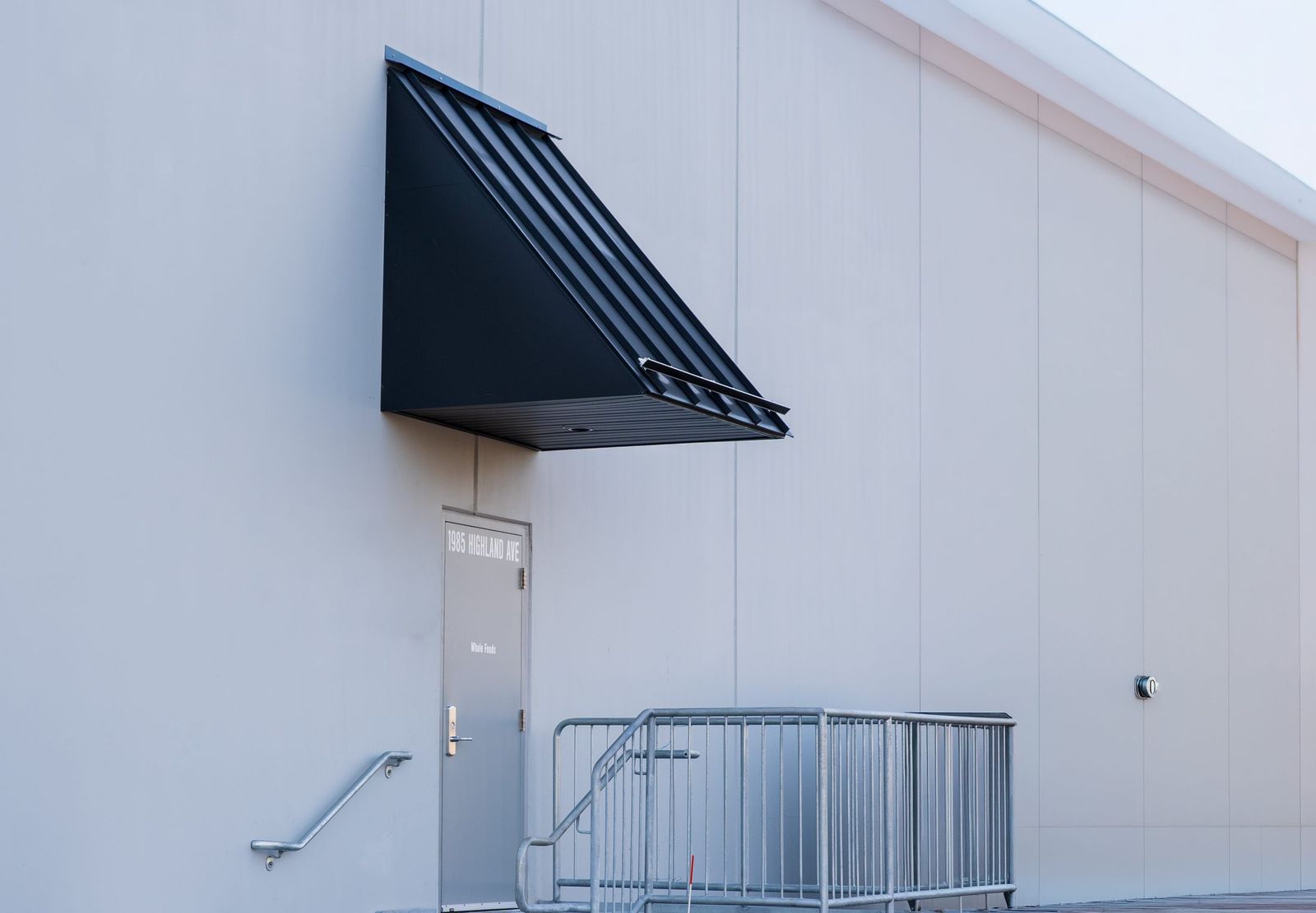 Angular black metal entrance canopy at a Whole Foods service entrance by Manchester Awning