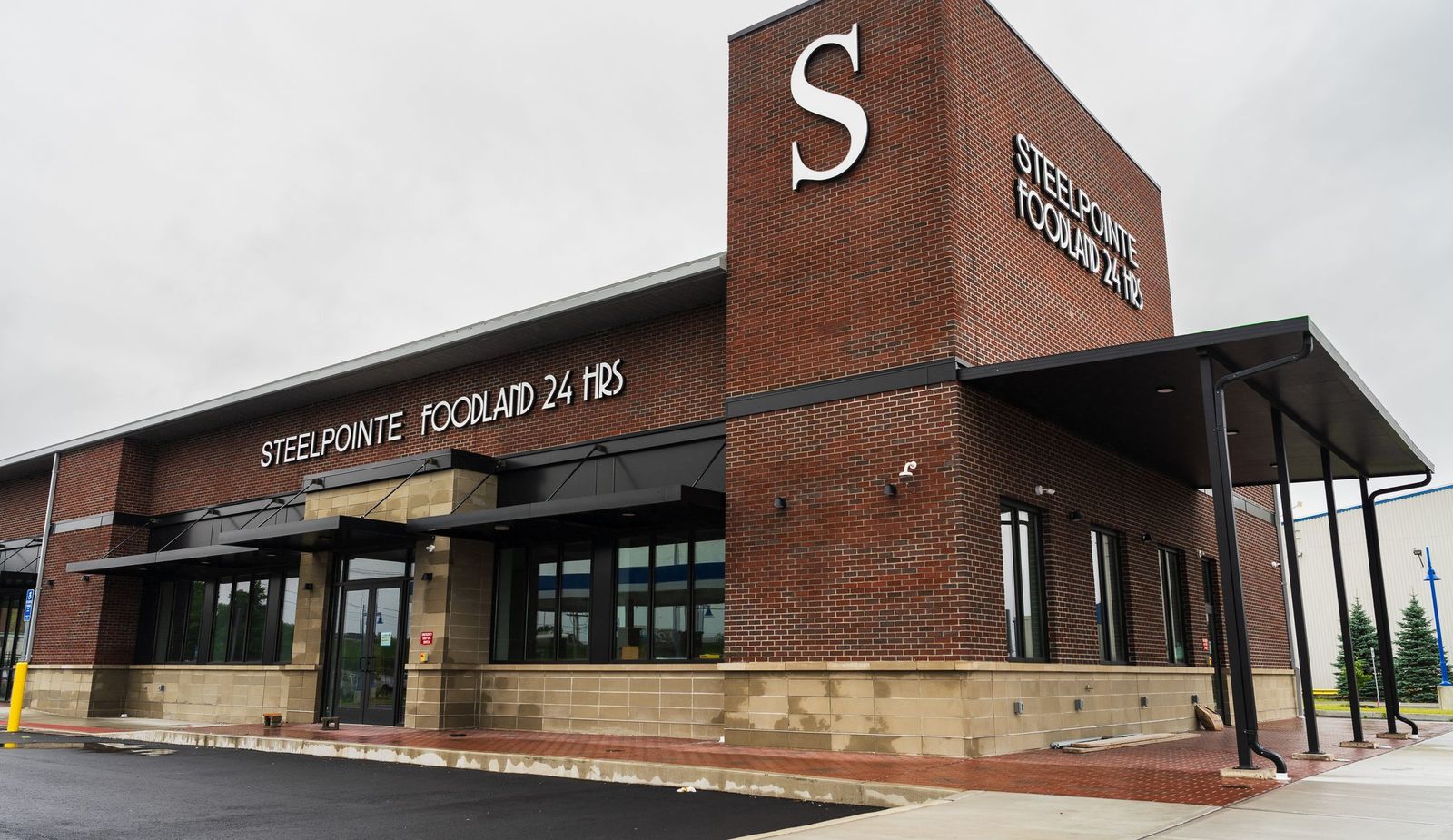 Steelpointe Foodland supermarket with black metal canopies and brick signage tower by Manchester Awning