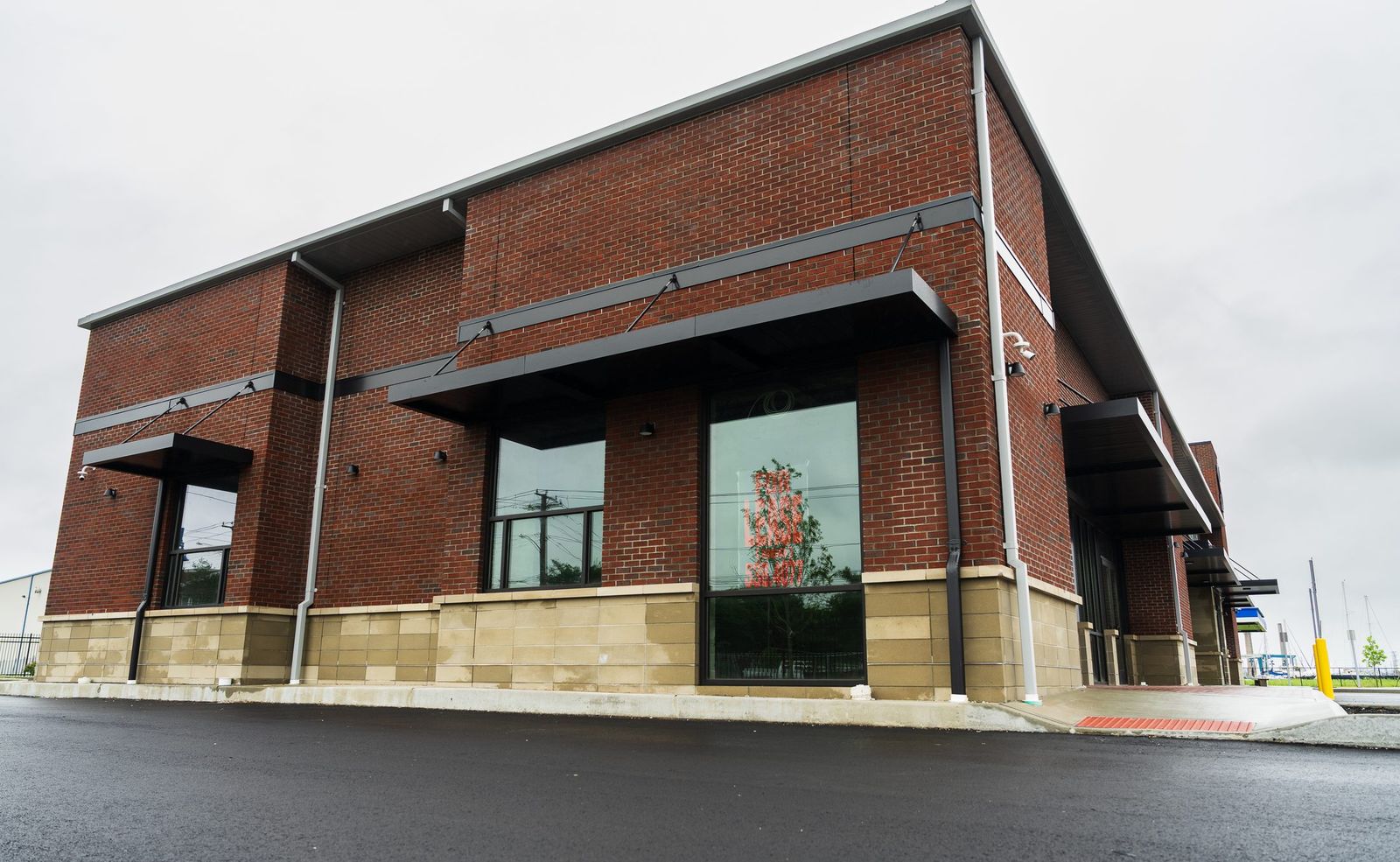 Cable-stay black metal window awnings on the brick facade at Steelpointe Foodland by Manchester Awning