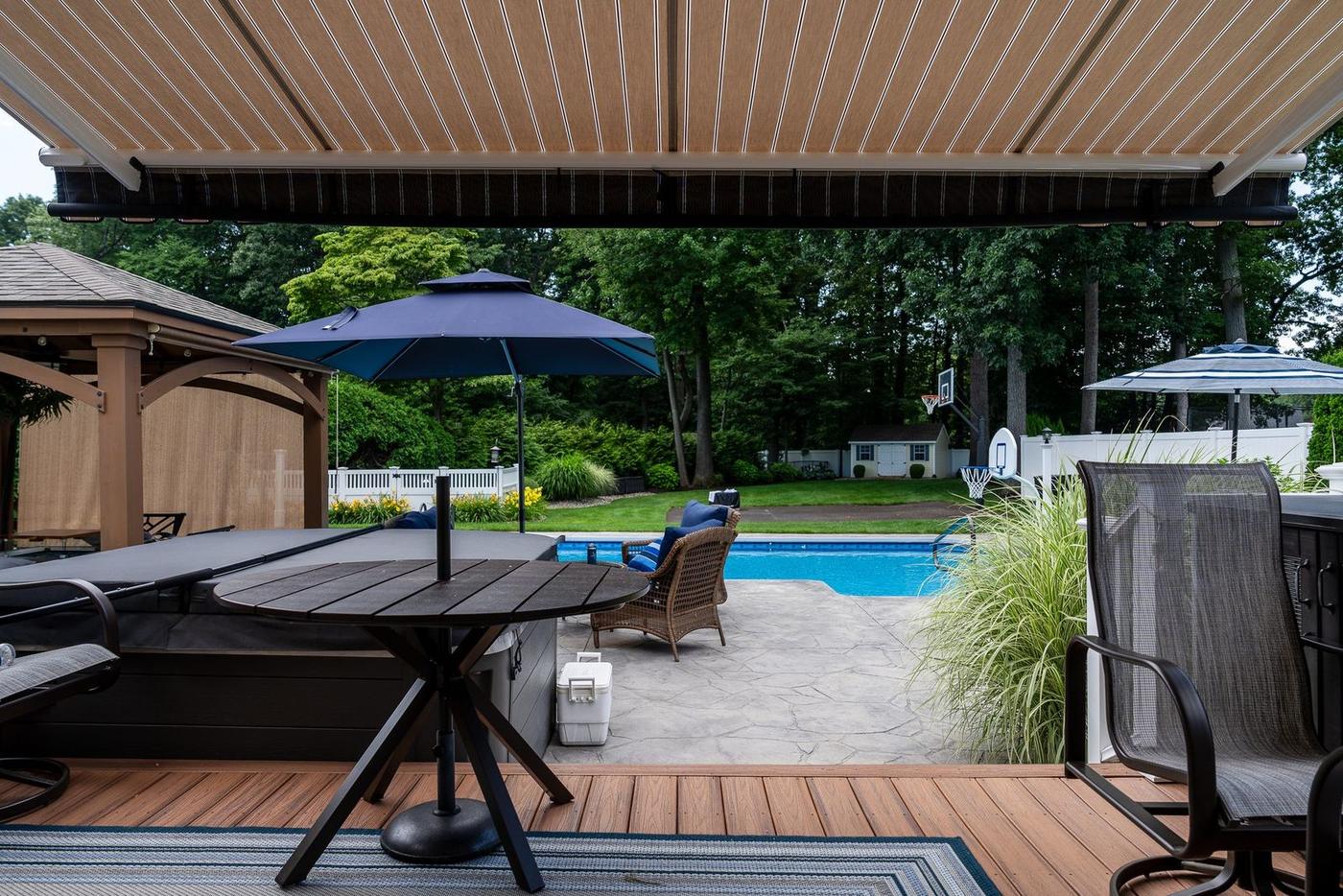 Shaded view from under a retractable awning overlooking a Connecticut backyard pool, by Manchester Awning